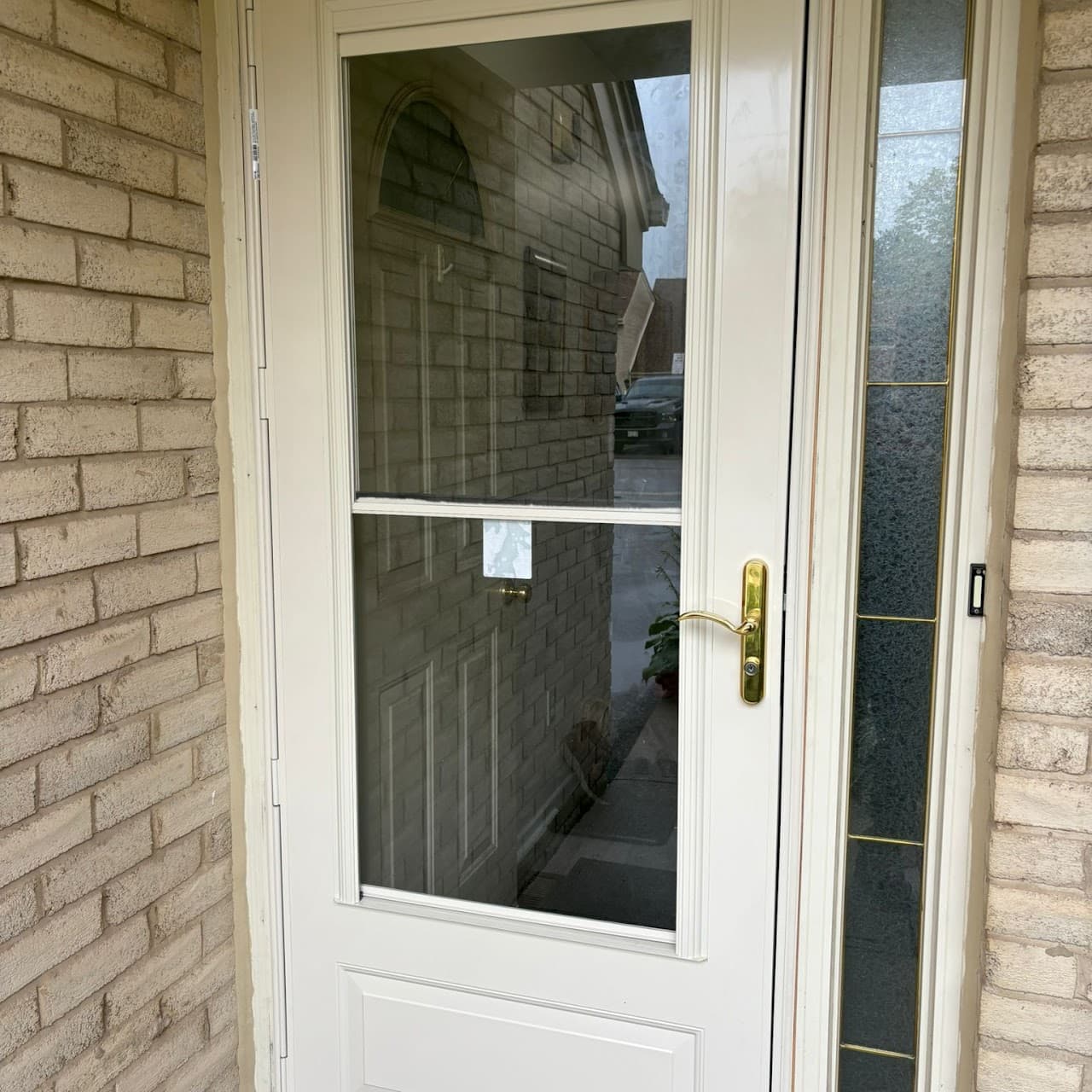 White aluminum-frame full-view storm door with gold lever handle - installed by LuminaSky Glass